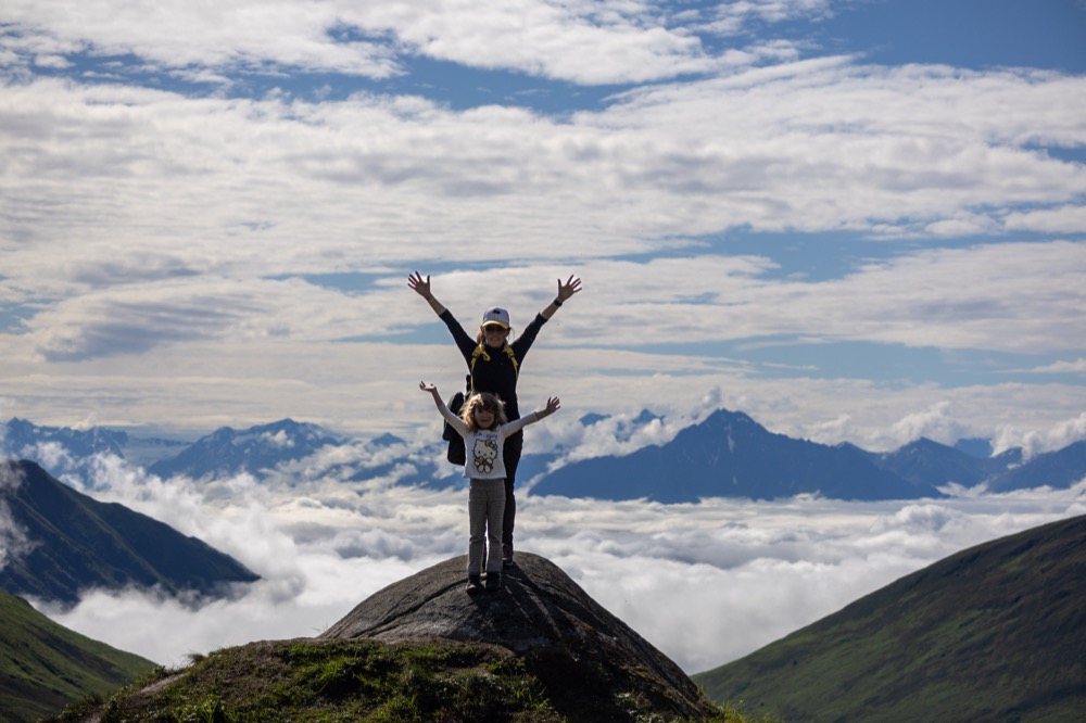 Ana and Lilli cheering on a rock above the clouds